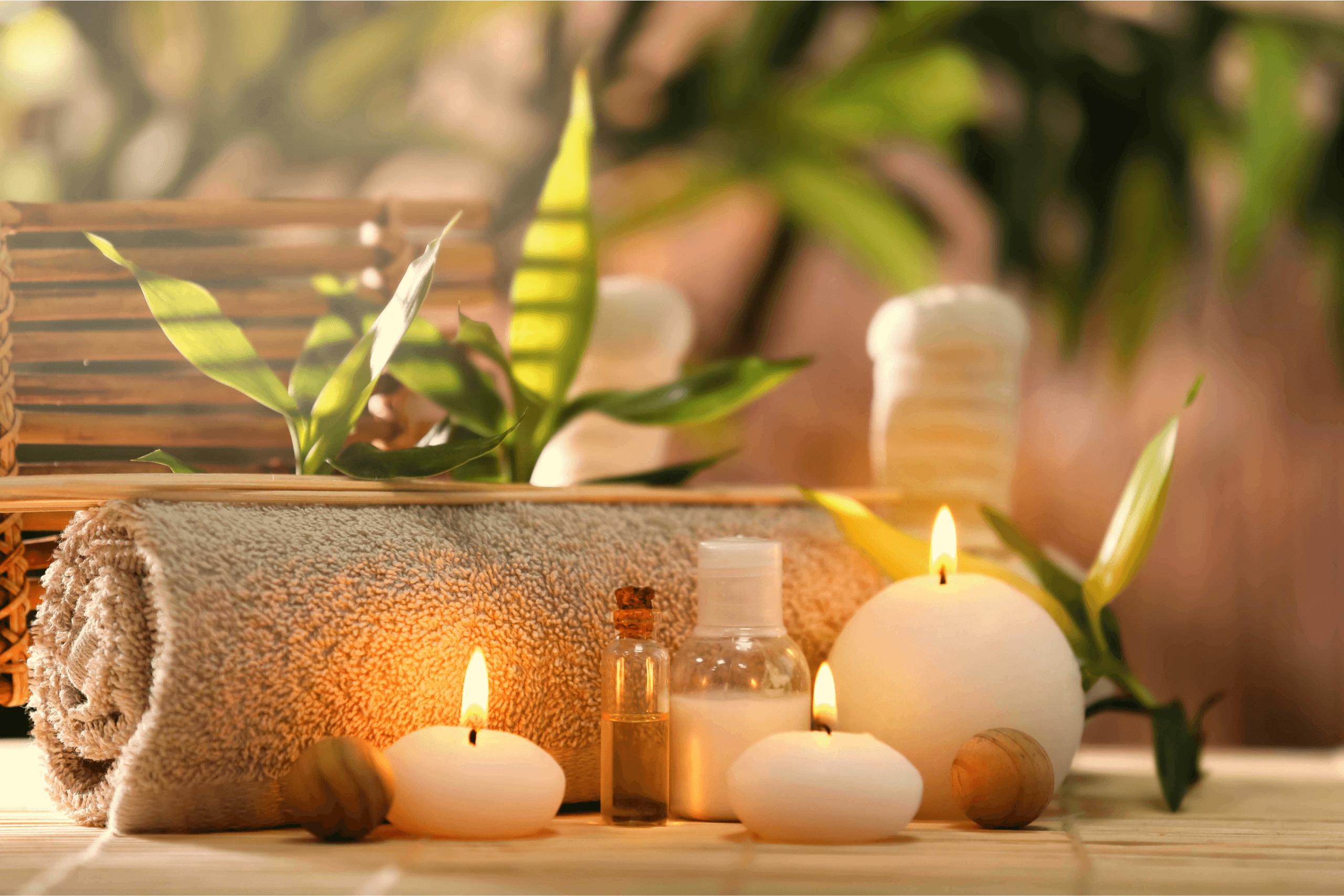 Candles, oil, plants, and a hot towel at a relaxing spa. 
